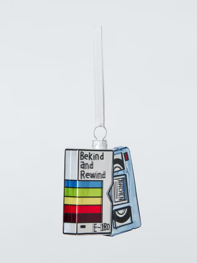 A hanging Christmas tree ornament shaped like a retro video cassette tape and case. Text on the sleeve reads